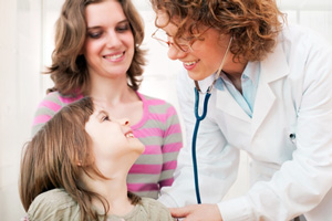 patient advocate stands next to her client while the doctor listens to the child’s lungs with a stethoscope
